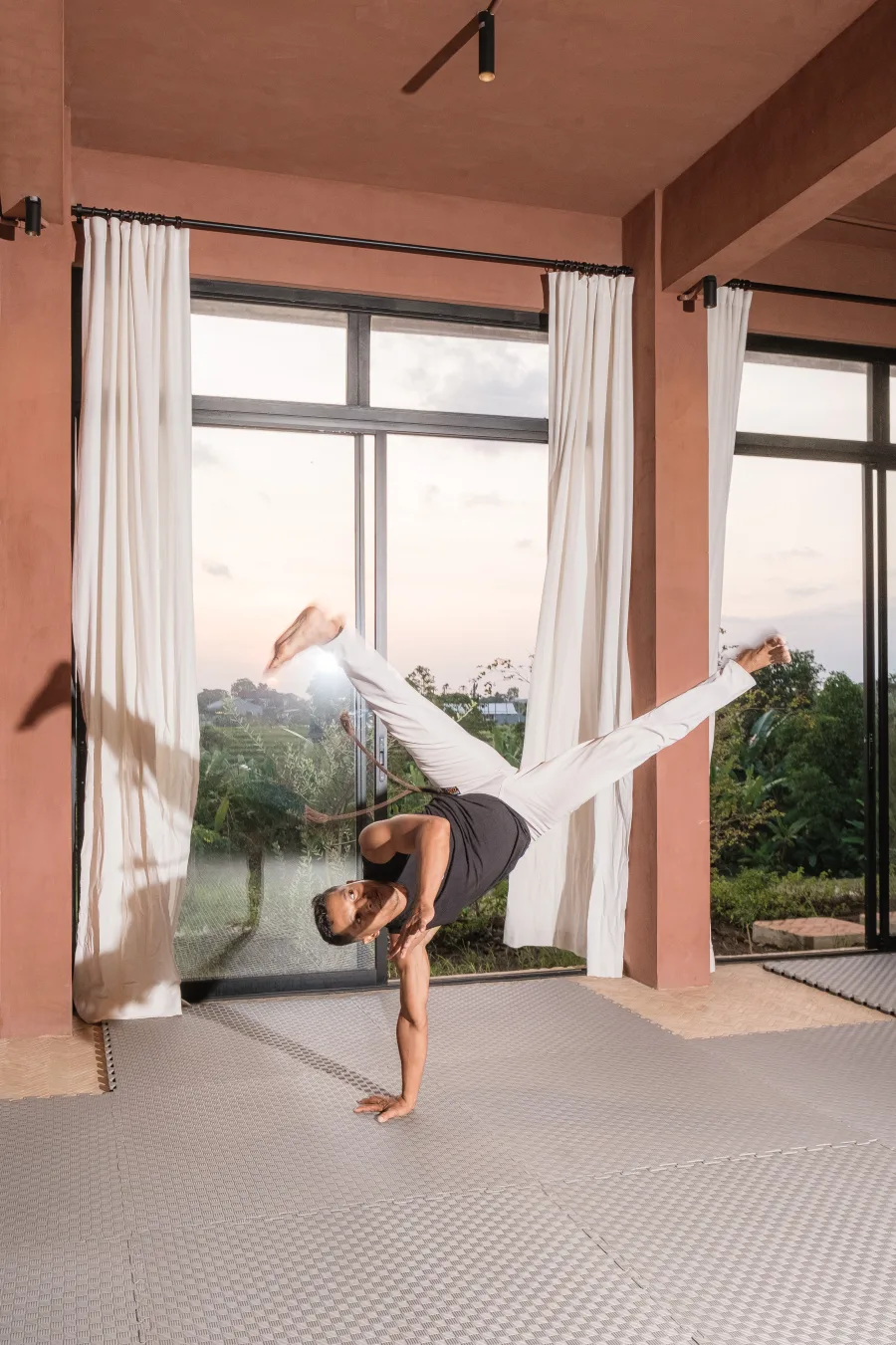 Capoeira teacher balancing on one hand beside the shala windows